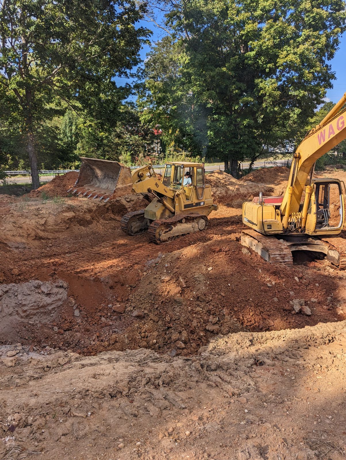 A bulldozer and a wheel loader are working on a dirt field.
