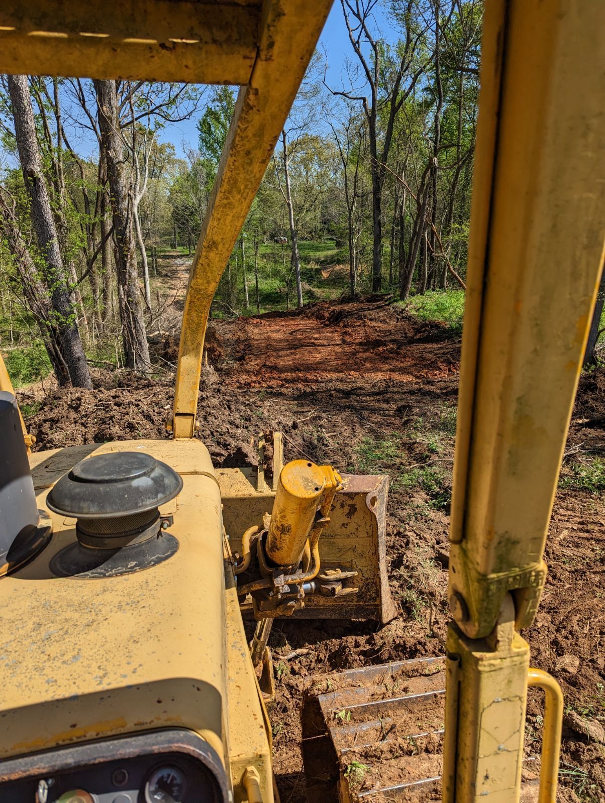 A yellow bulldozer is driving through a dirt field.