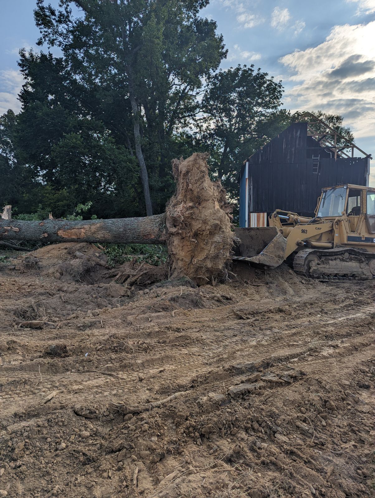 A bulldozer is moving a large rock in a dirt field.