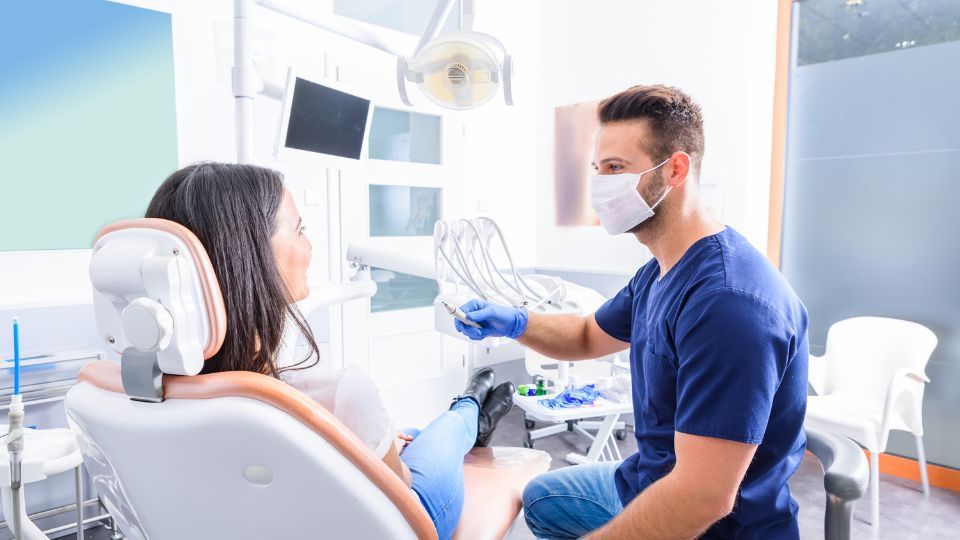 A dentist is talking to a patient in a dental chair.