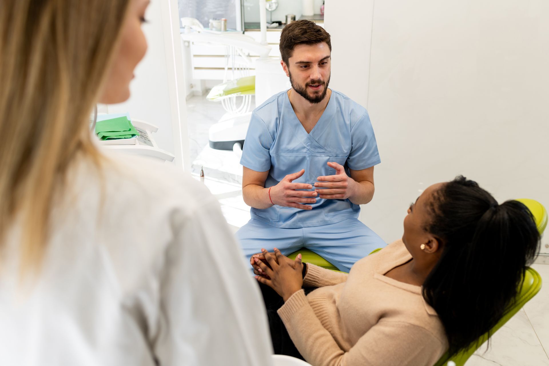 A woman is sitting in a dental chair talking to a dentist.