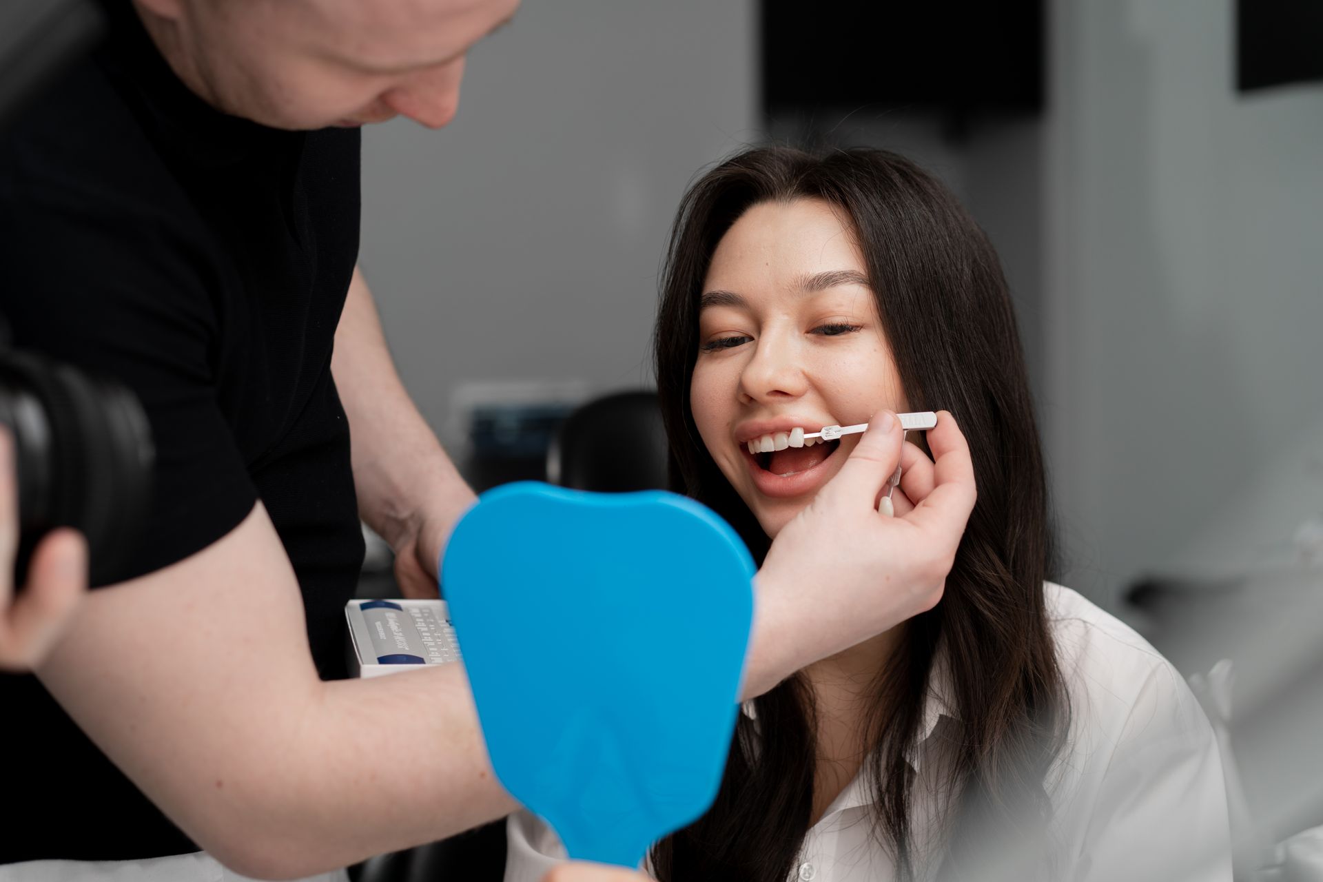 A man is taking a picture of a woman 's teeth in a mirror.