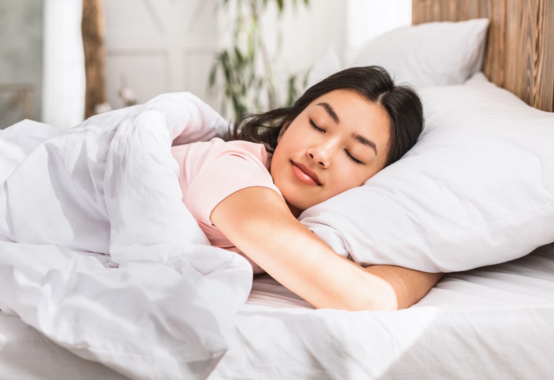 A woman is sleeping in a bed with white sheets and pillows.