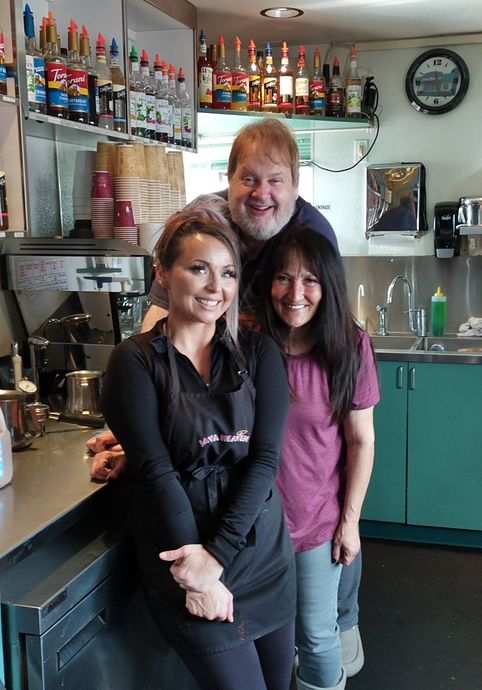 A man and two women are posing for a picture in a kitchen.