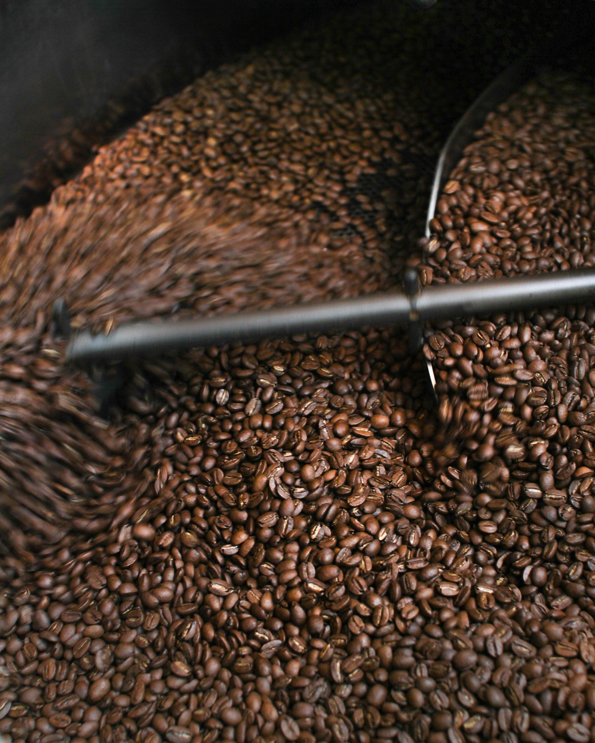 A pile of coffee beans is being roasted in a machine.