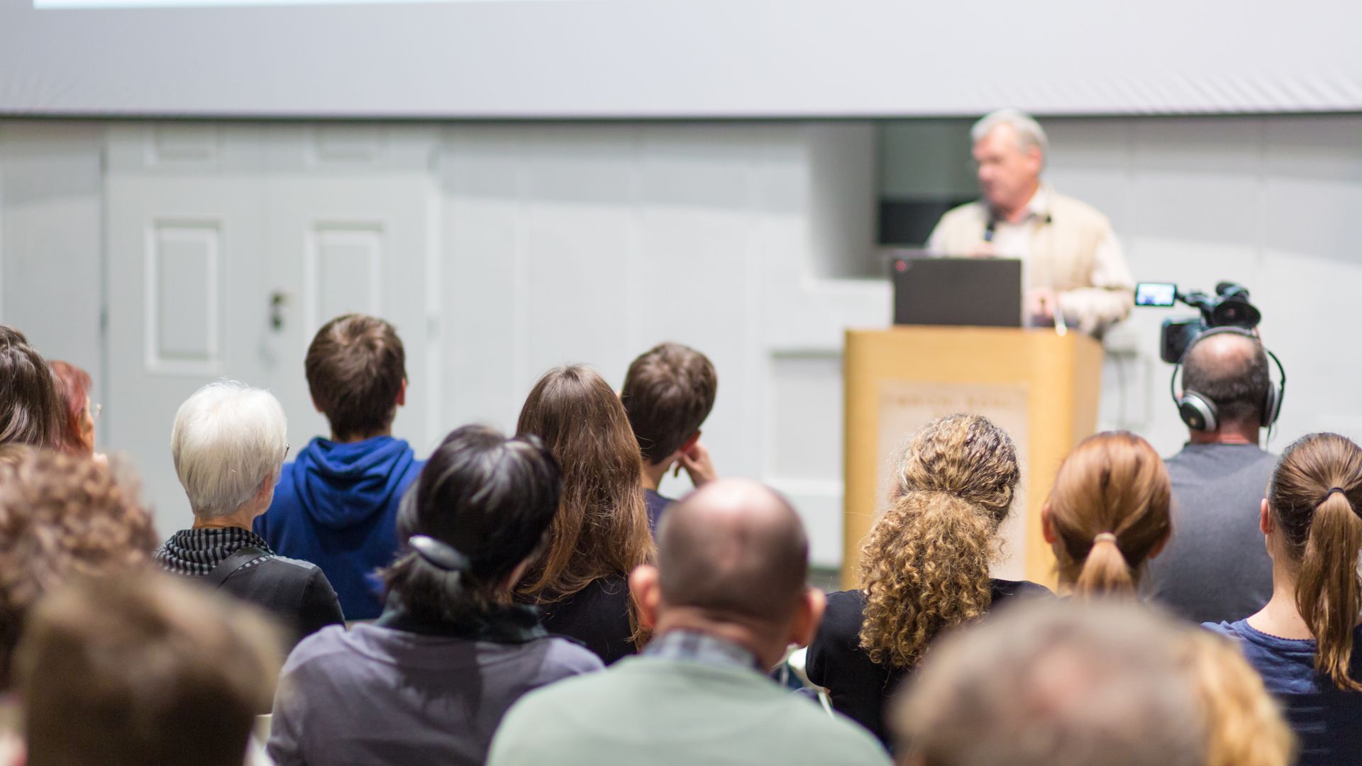 People shaking hands at an event with American flags in the background.
