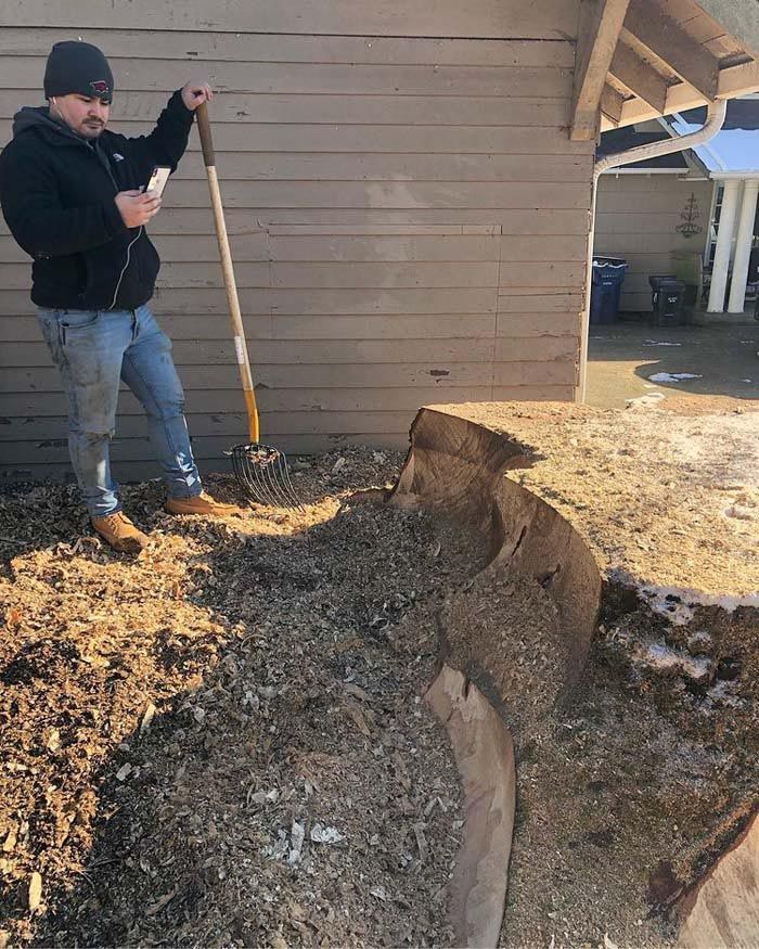 A man is standing next to a pile of dirt holding a shovel.