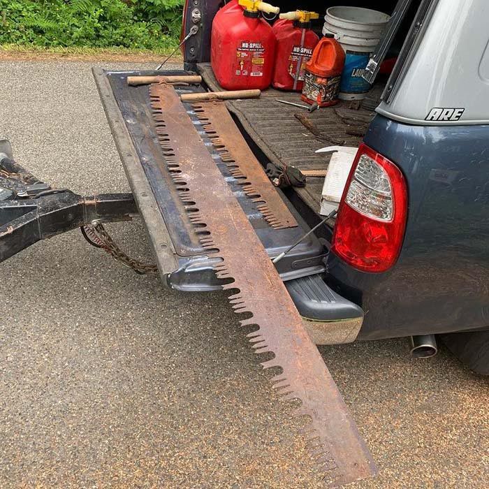 A large saw is attached to the back of a truck.