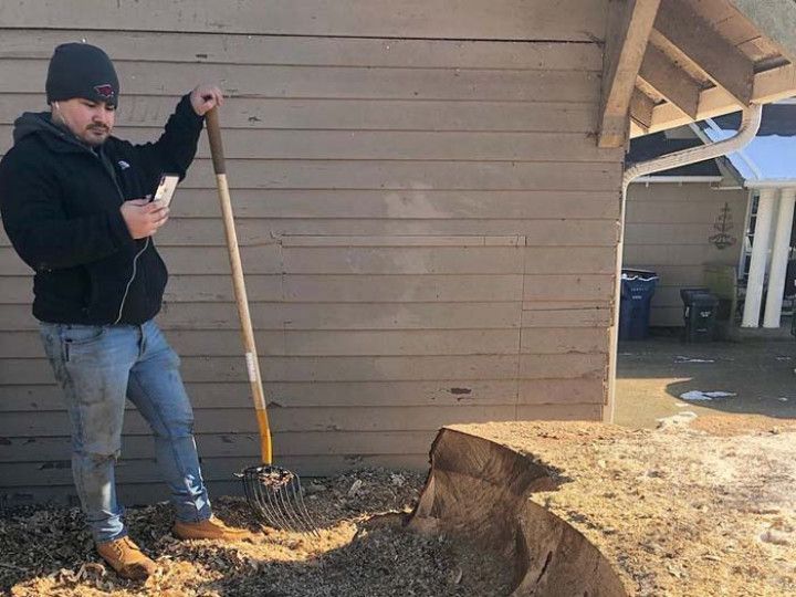 A man is holding a shovel in front of a house.