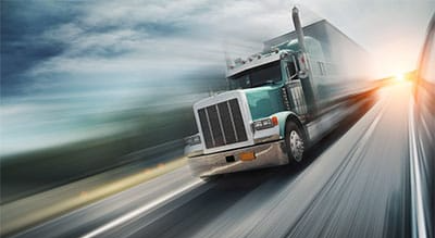 A semi-truck is driving down a highway.