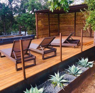 Wooden deck with lounge chairs and agave plants, shaded by a slat-walled pergola.
