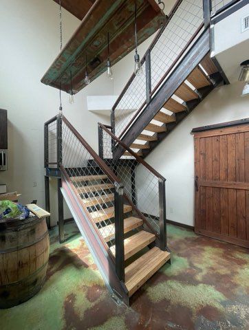 Industrial staircase with wooden steps, metal frame, and wire mesh railing.