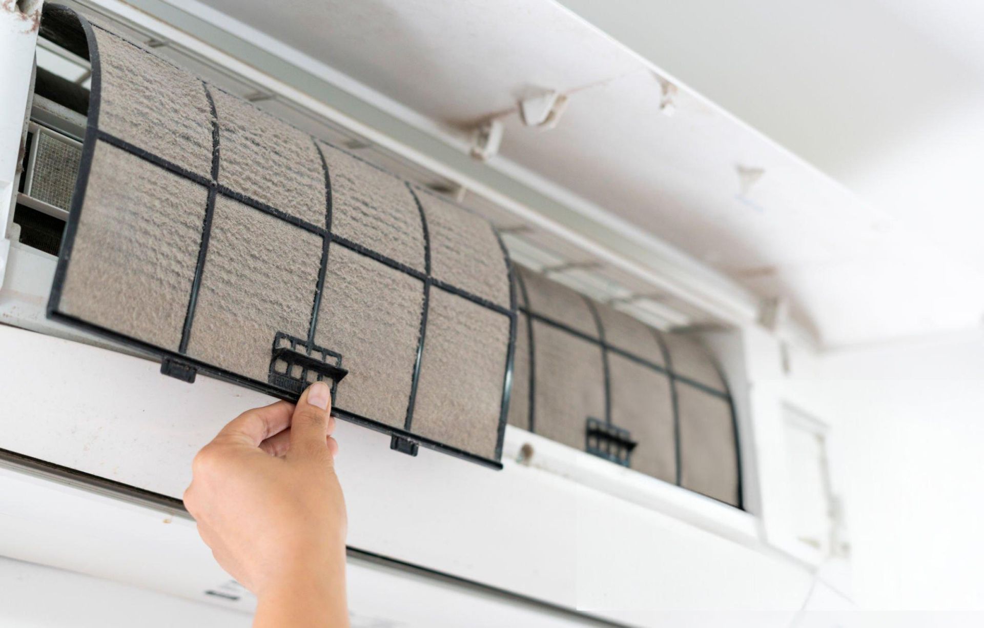 A person is cleaning the filter of an air conditioner.