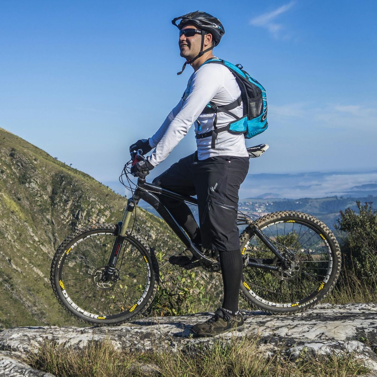A man with a backpack is riding a bike on top of a mountain.