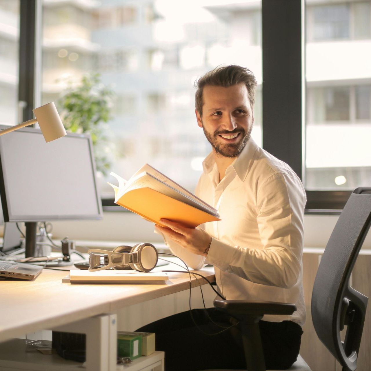 A man is sitting at a desk reading a book