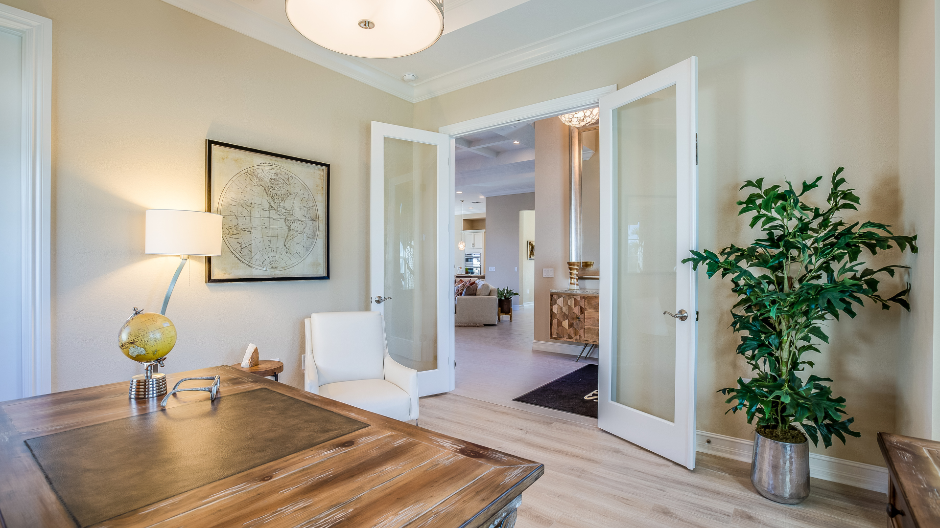 A home office with a desk , chair , lamp and potted plant.