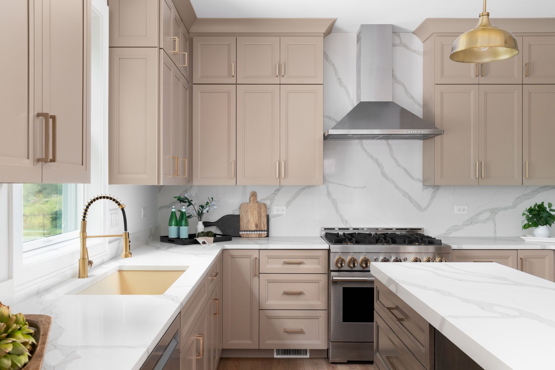 Tan kitchen with white countertops, stainless steel range, and gold fixtures.