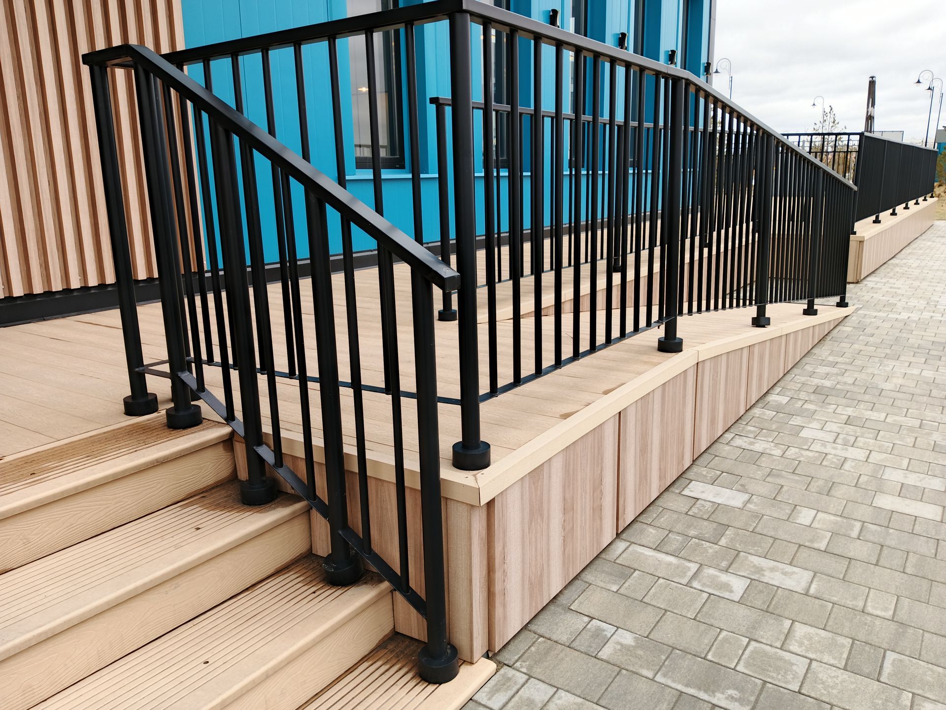 Black metal handrail on stairs and ramp with tan wood siding.