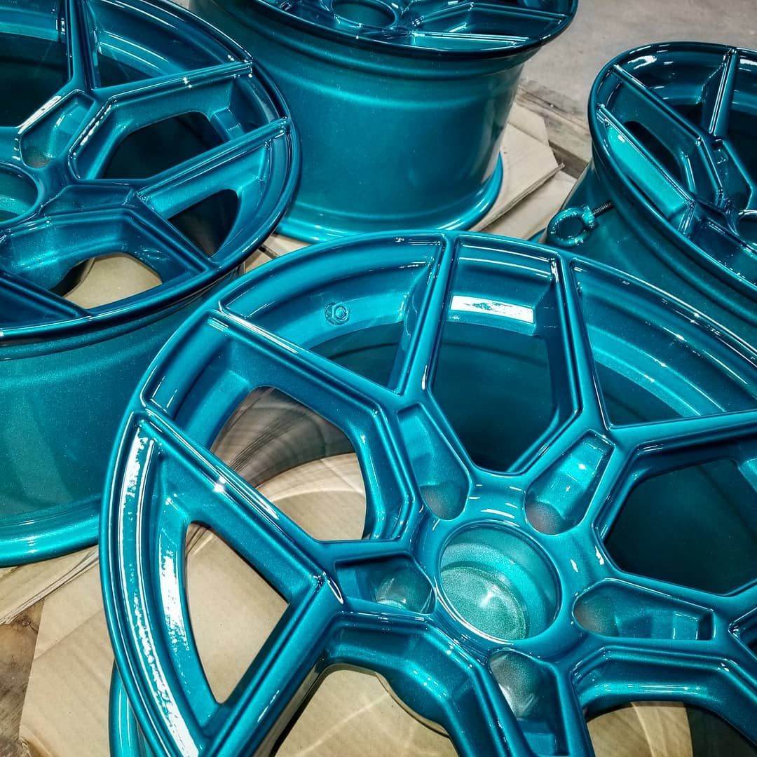 Four turquoise-colored car wheels arranged together.