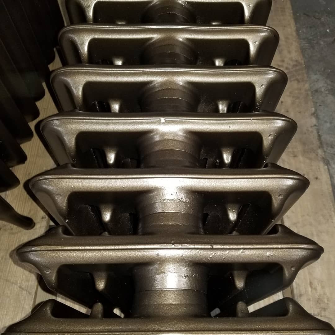 Stack of vintage cast iron radiator sections, metallic gray, indoors.