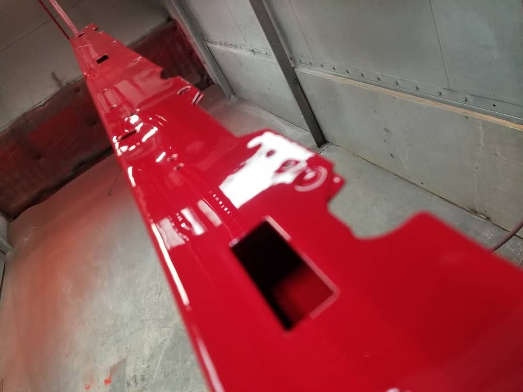 Red painted metal part inside a spray booth.