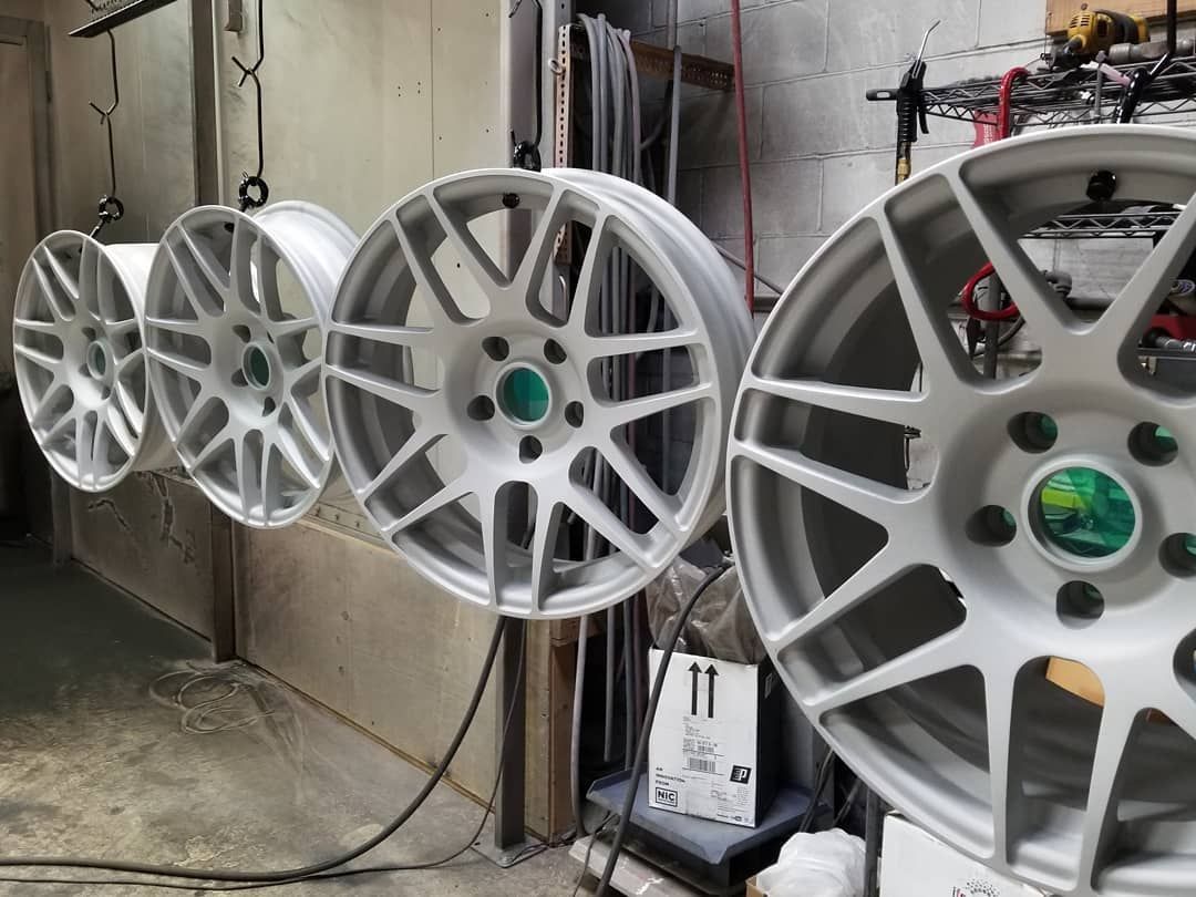 Four silver car wheels hanging in a workshop, ready for the next step of a project.