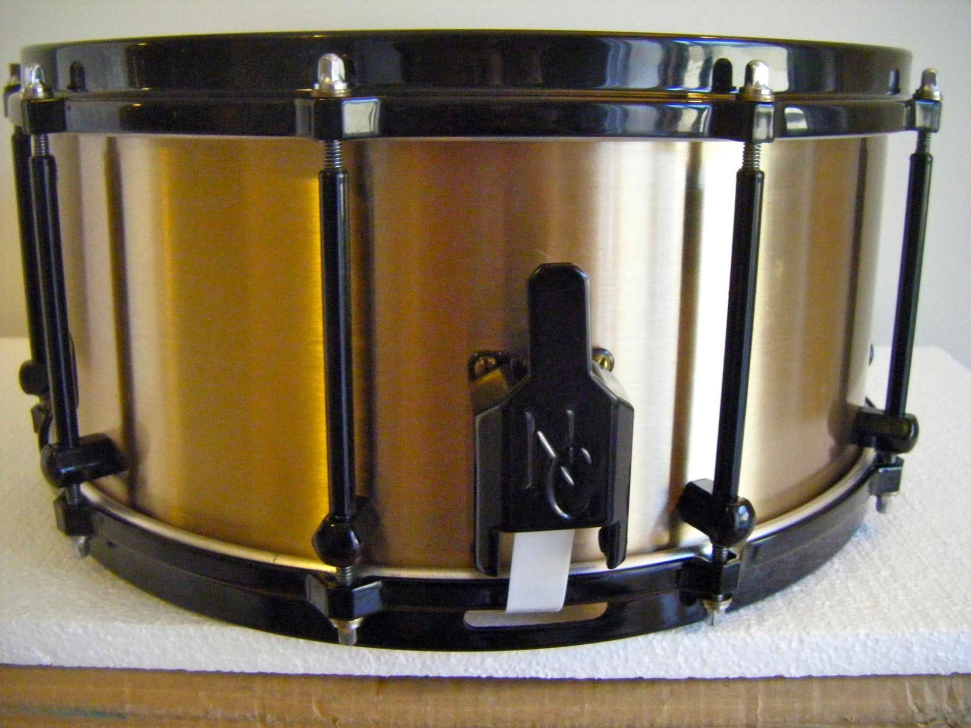 Brass-colored snare drum with black rims and hardware.