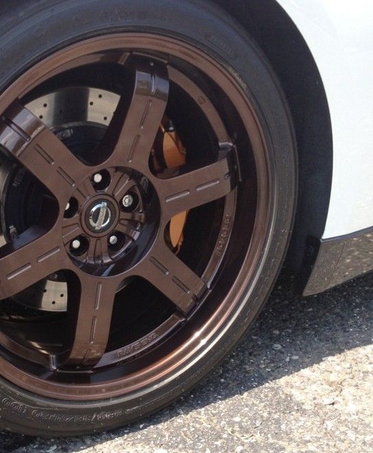 Metal parts in various colors, hanging on racks in a workshop, likely for painting or coating process.