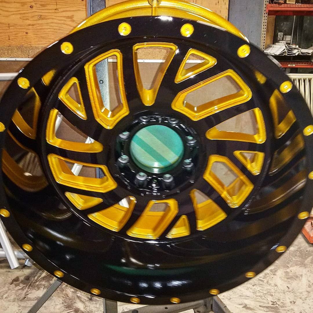 Black and gold custom car wheel on a stand.