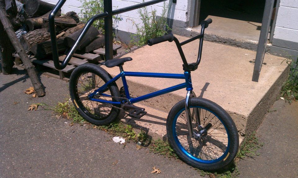 Blue BMX bike parked on concrete near a building.