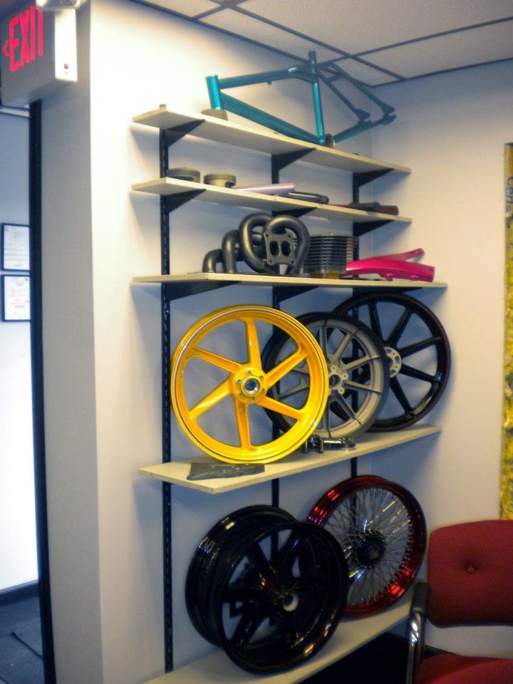 Shelves displaying various bicycle parts, including frames, wheels, and components in different colors.
