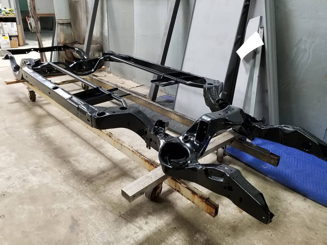Black car frame on a workbench with casters.