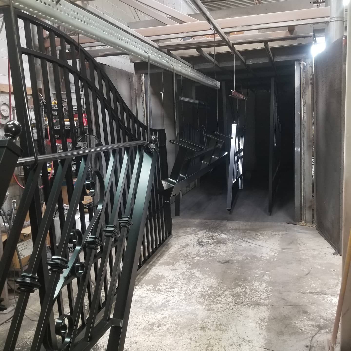 Black metal gates and railing inside a powder coating booth.