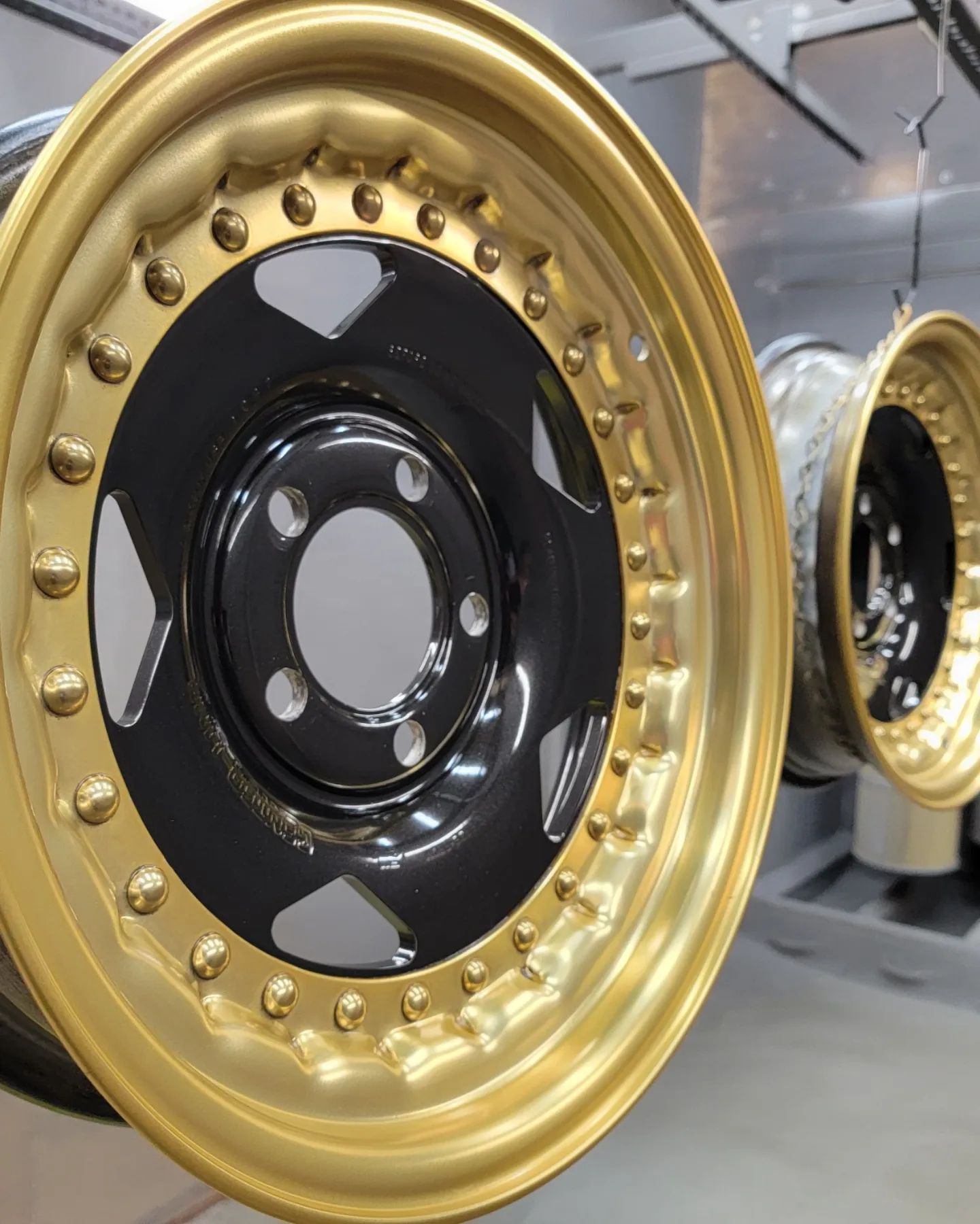 Gold and black custom car rims hanging in a shop.