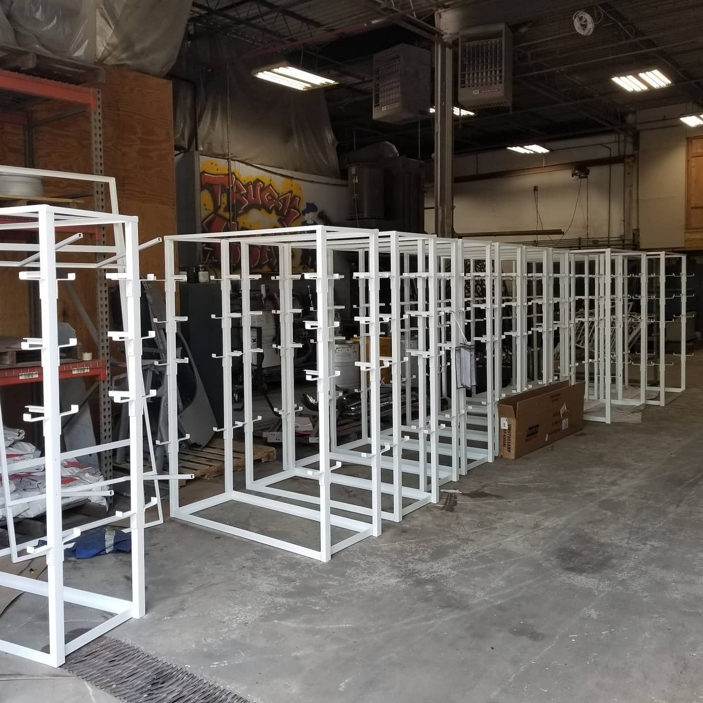 White metal frames lined up in a workshop, possibly for shelving or display.
