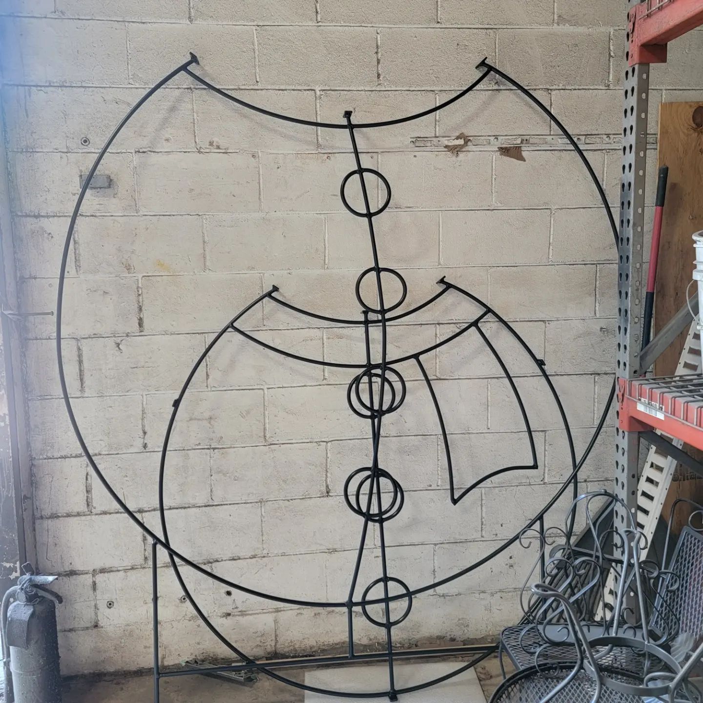 Black metal sculpture resembling a stylized face against a brick wall.