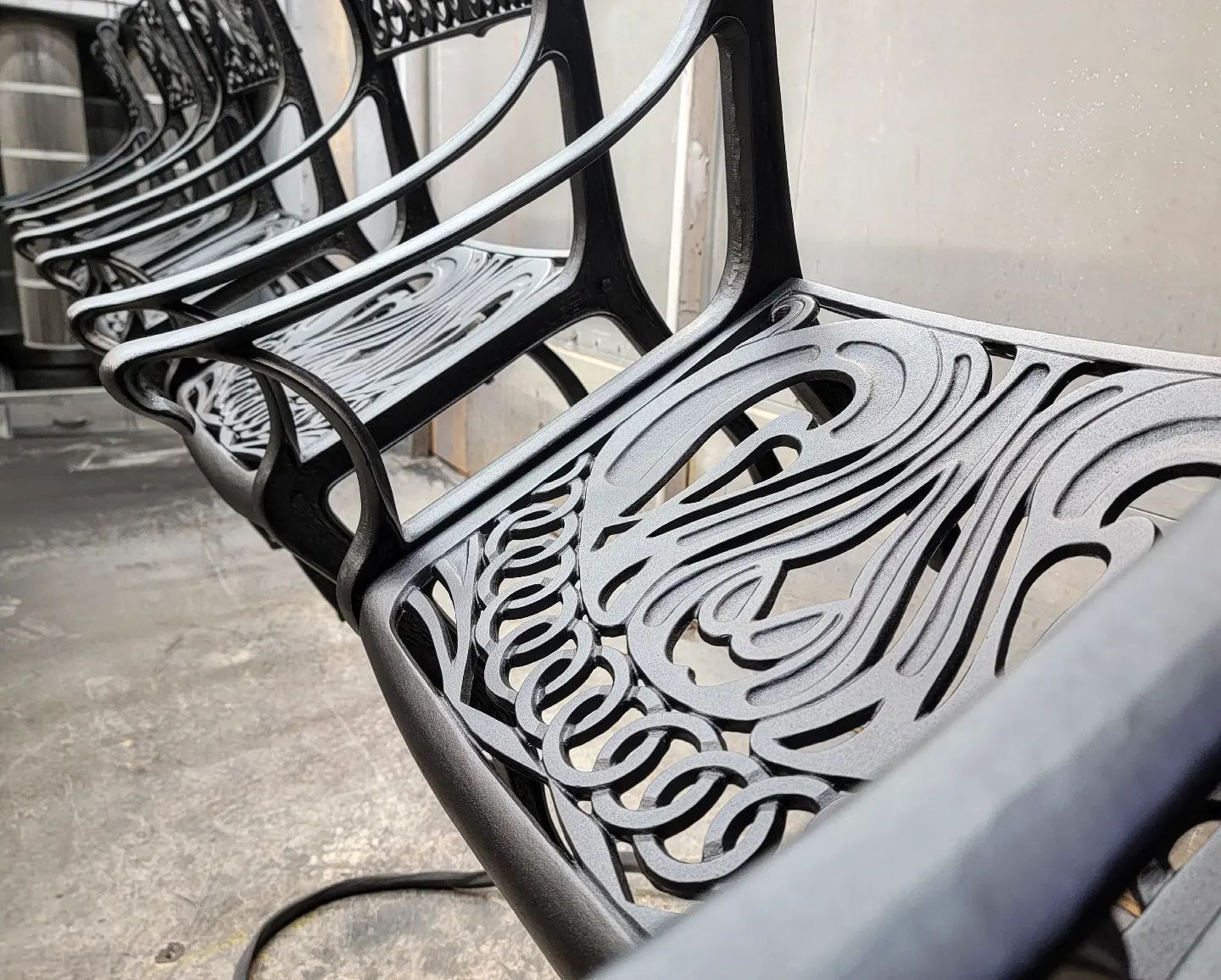Black metal benches with ornate designs in an outdoor setting.