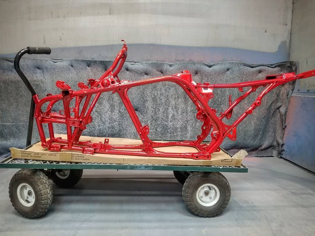 Red ATV frame on a small green cart, likely after painting.