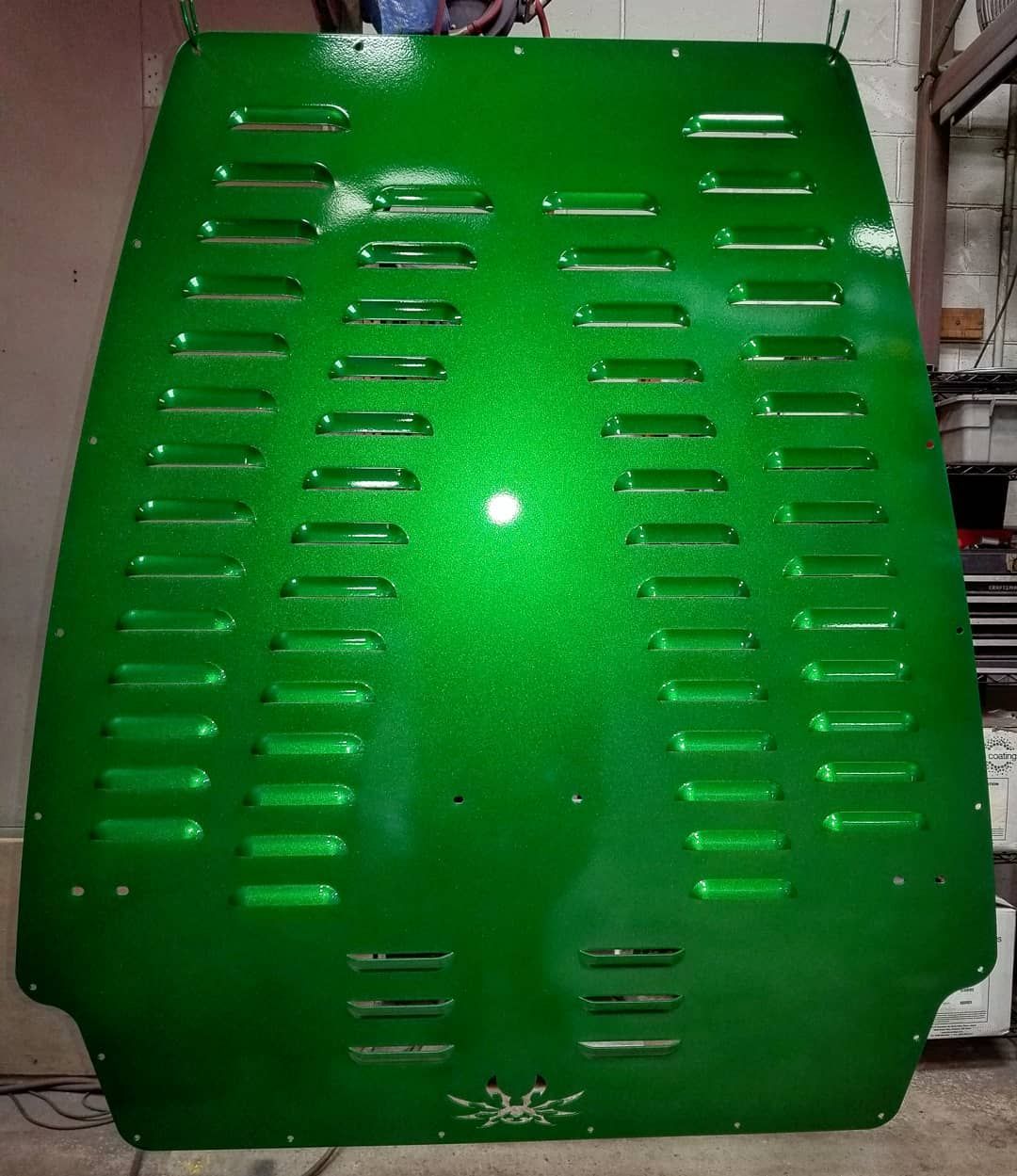 Green metal hood with slotted vents, a reflective surface, and a small emblem.