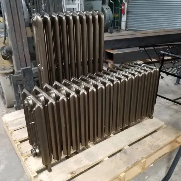 Antique cast iron radiators on a wooden pallet in a workshop, brown in color.
