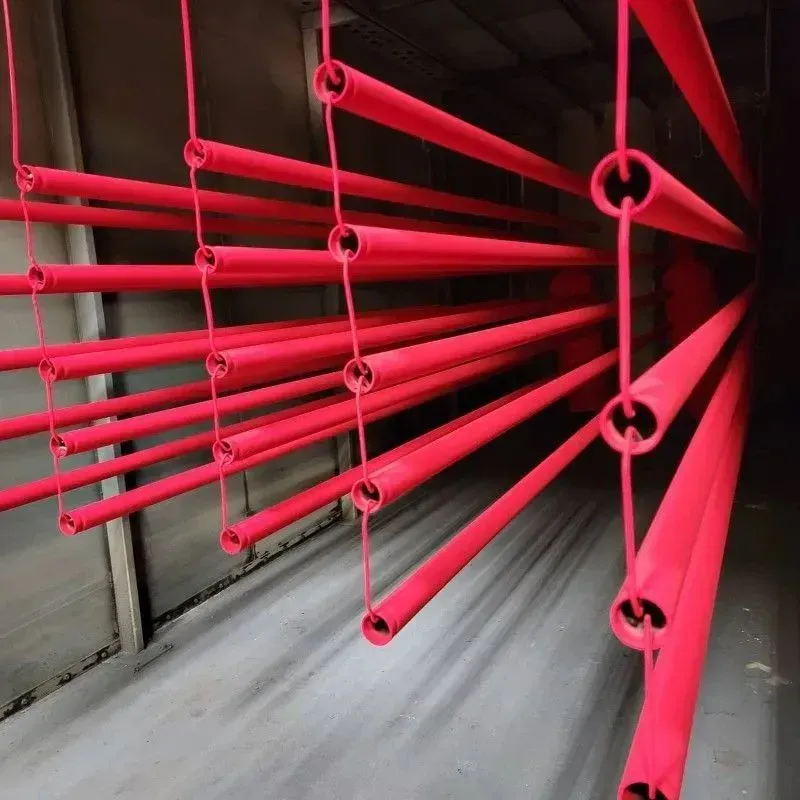 Red metal tubes hanging in an industrial setting, likely for powder coating.