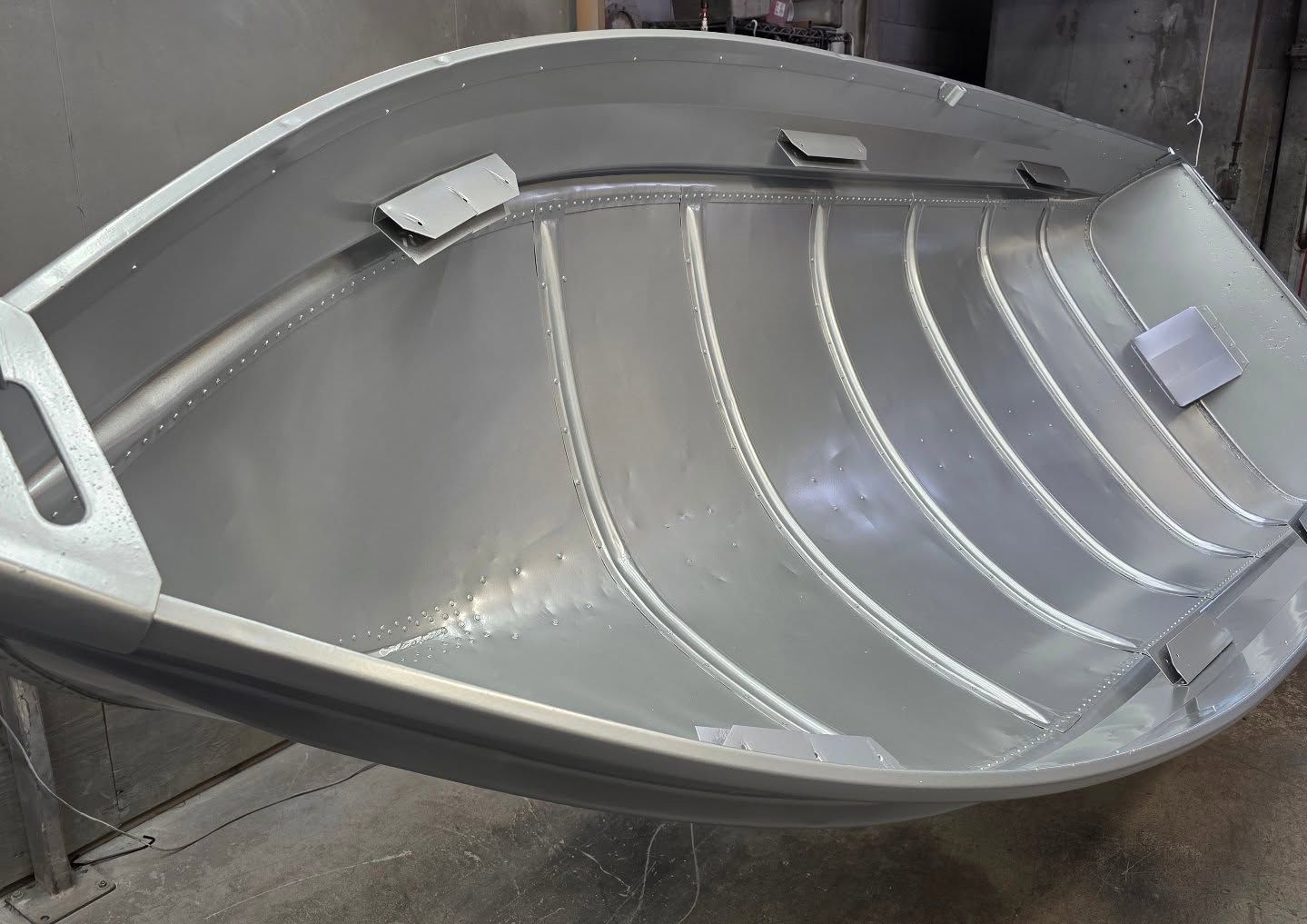 Empty aluminum boat interior, showing ribs and metal construction.