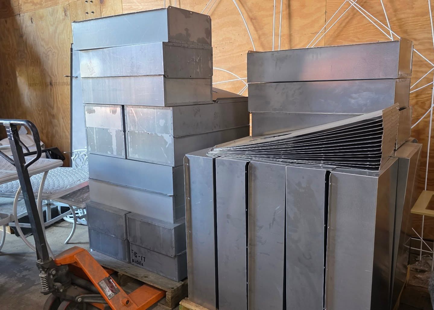 Stacks of gray metal blocks on wooden pallets inside a wooden structure.