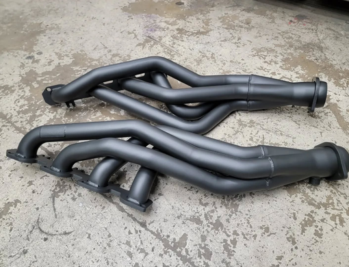 Two cast iron exhaust manifolds, light gray, with multiple mounting holes.