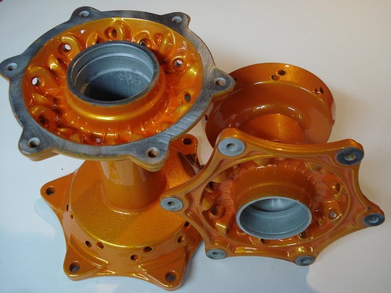 Orange metal hubs with bolt holes; a close-up on a white surface.