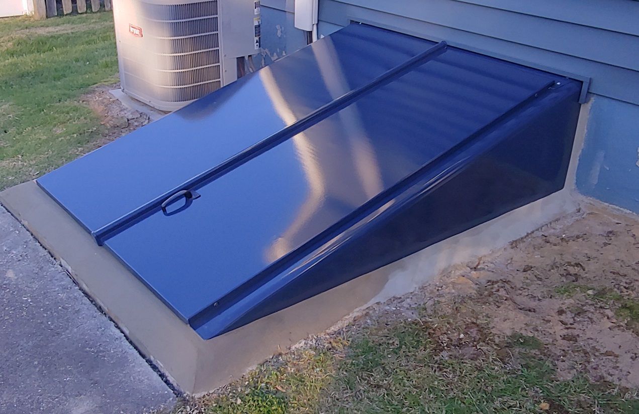 Blue basement door built into a concrete slab on the side of a house.