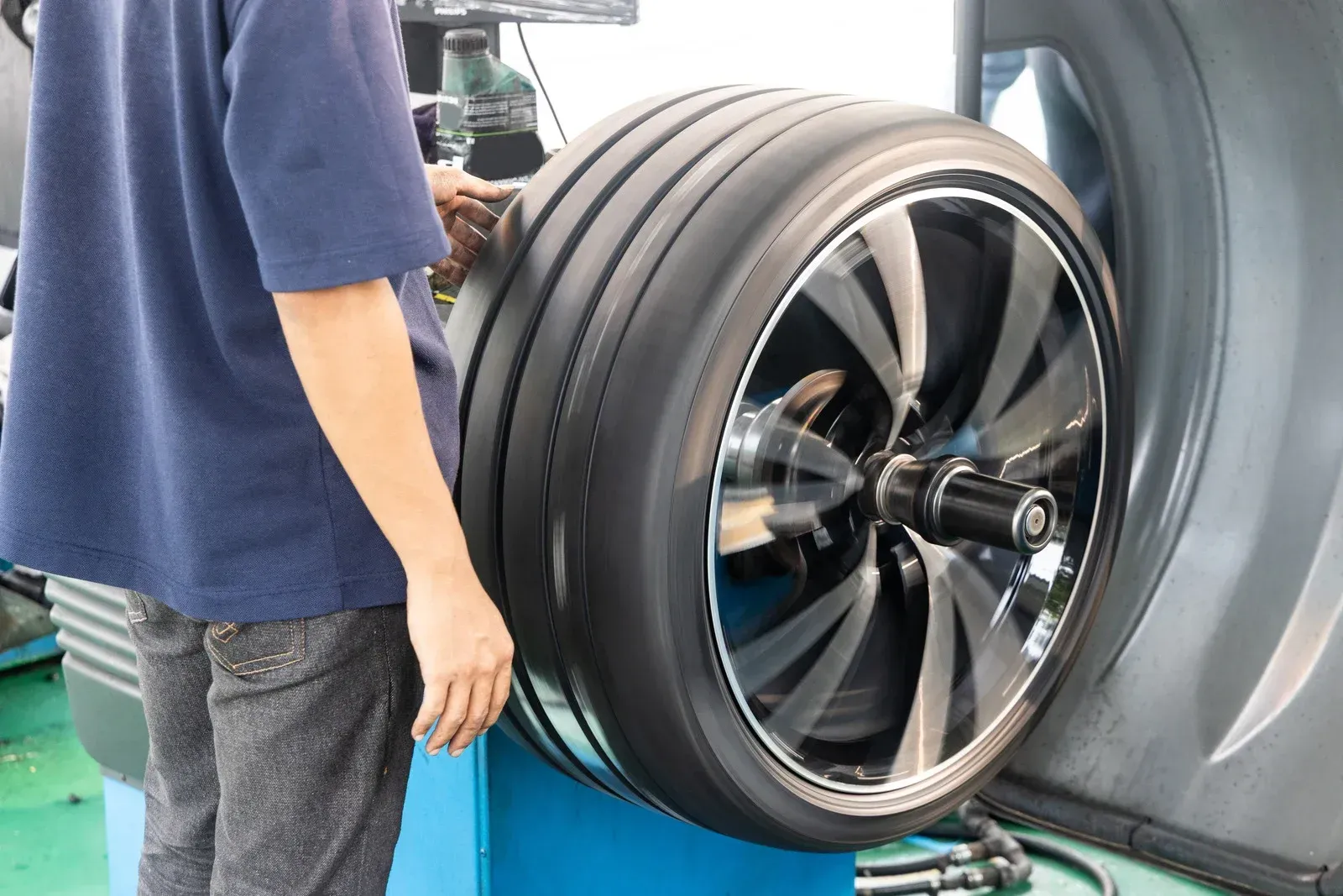 Mechanic balancing a car tire on a machine, checking for even weight distribution.