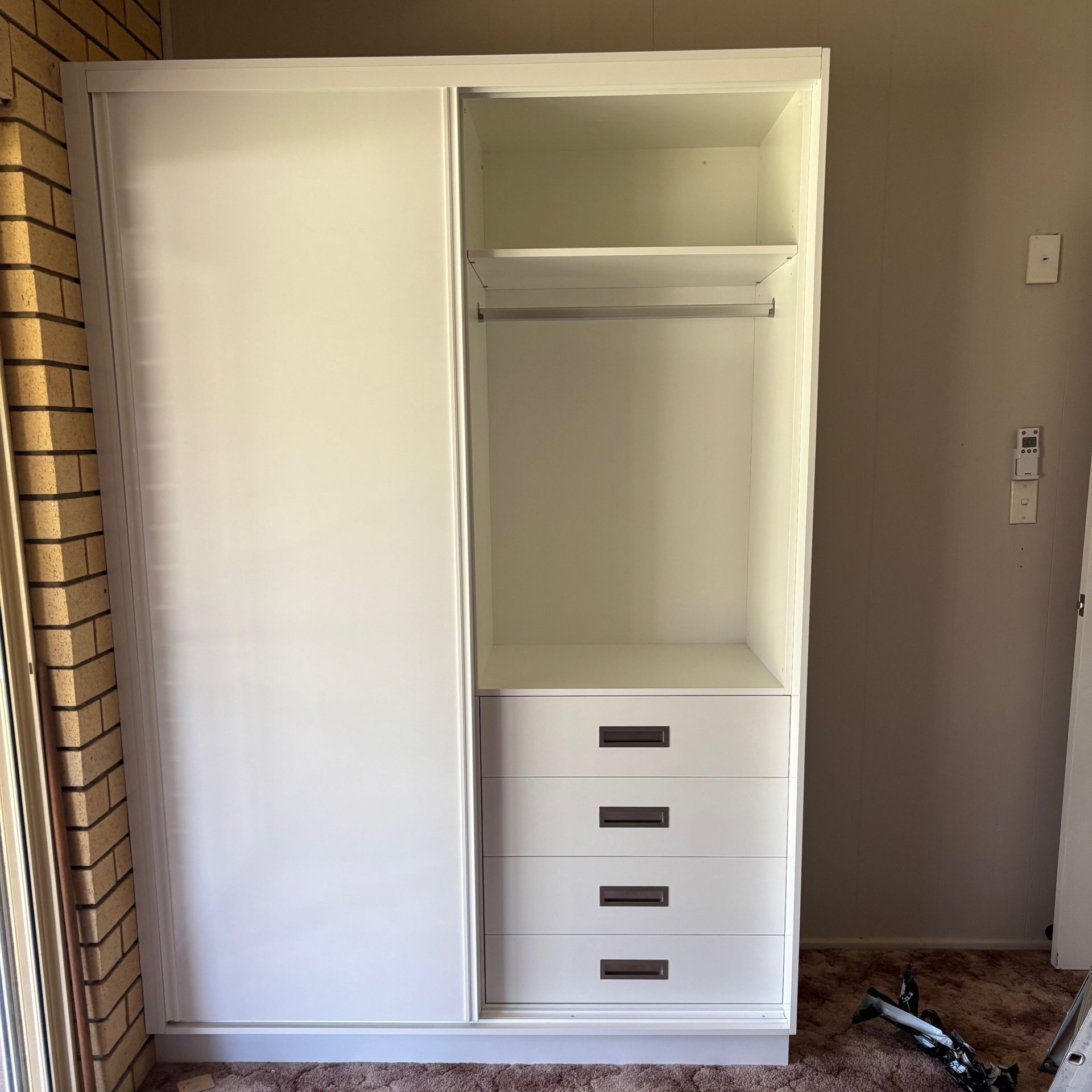 A White Wardrobe With Sliding Doors and Shelves in a Room — Crispin Cabinetmakers in Maclean, NSW