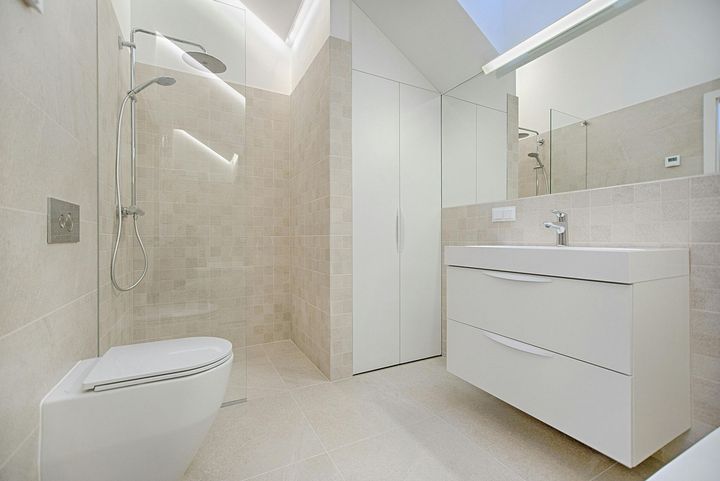 Modern bathroom with white fixtures, beige tile, and a shower.