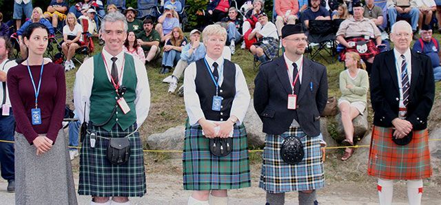 A group of people in kilts are standing in front of a crowd.